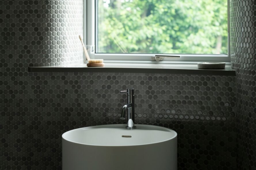 lavabo de la salle de bain devant une grande fenêtre carrée
