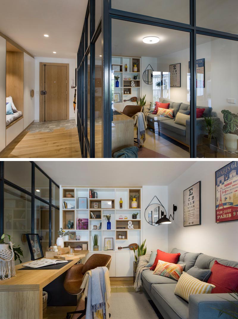 À l'intérieur de ce bureau à domicile vitré moderne se trouve un long bureau en bois qui rencontre une étagère conçue sur mesure, avec certaines des étagères bordées de bois. En face du bureau se trouve un canapé gris confortable, quelques plantes et des oreillers colorés, tandis qu'un tapis ajoute une touche douce sous le pied. #HomeOffice #GlassWalls #Shelving