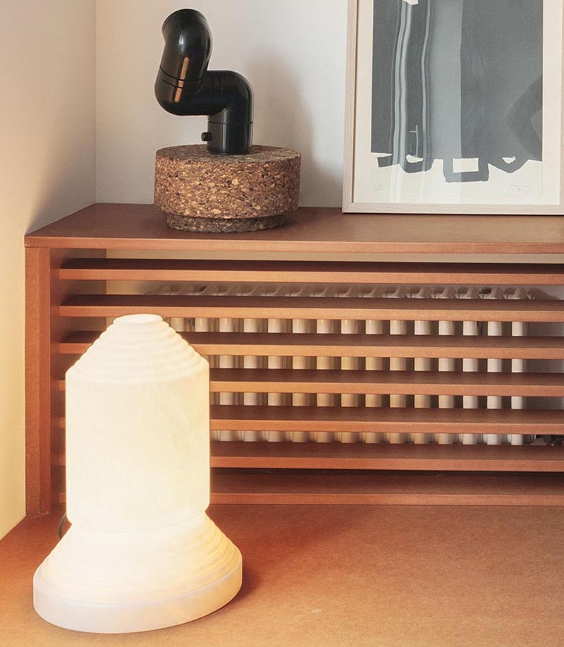 Une étagère conçue sur mesure avec une façade en lattes de bois est utilisée pour cacher le radiateur bien en vue dans le salon de cet appartement moderne. #HideRadiator #Radiator #LivingRoom