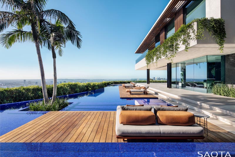 Les multiples terrasses en bois, qui descendent des principaux espaces de vie de l'intérieur, sont idéales pour se détendre au bord de la piscine et ont suffisamment de place pour les transats, les banquettes-lits, les tables d'appoint et les poufs. #SwimmingPool #PoolDeck #Deck #Architecture #PoolDesign