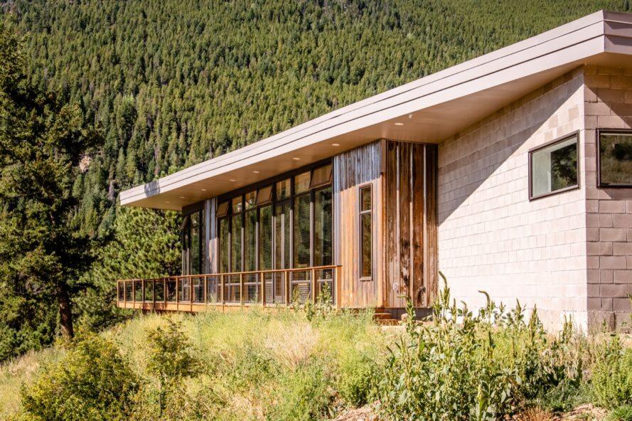 maison en acier avec toit incliné entouré de forêt