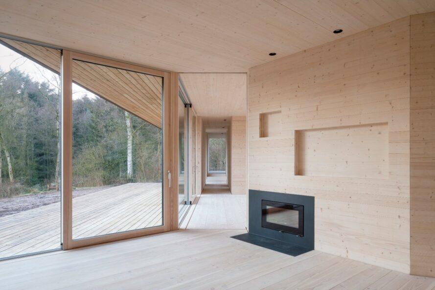maison légère bordée de bois avec petite cheminée et un mur de verre