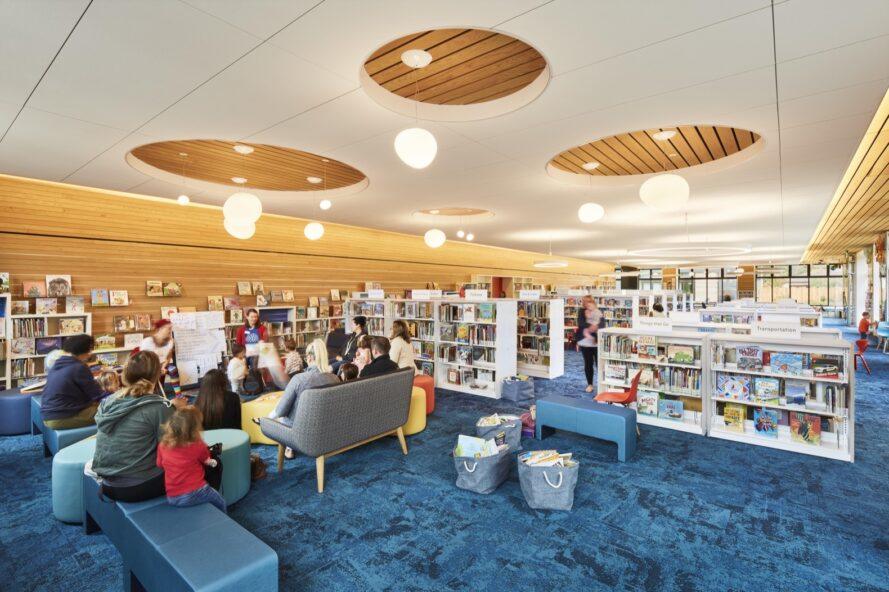 les gens se sont réunis en cercle dans une salle de bibliothèque bleu et blanc