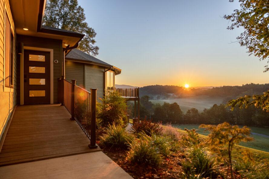 Passerelle menant à la maison avec coucher de soleil sur les montagnes à l'horizon