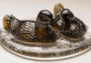 Une série étincelante de canards en verre pressé sculptés dans des flaques d’eau