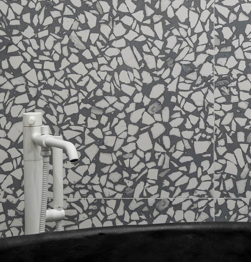 Une tuile de grand format agrégée grise et blanche a été installée dans cette salle de bain moderne et couvre les murs et le sol, créant une expérience presque artistique lors de l'utilisation de la salle de bain. #GreyAndWhiteBathroom #GreyBathroom #BathroomIdeas #AggregateTiles