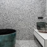 Les carreaux de terrazzo blanc et gris couvrent complètement les murs et le sol de cette salle de bain avec une baignoire