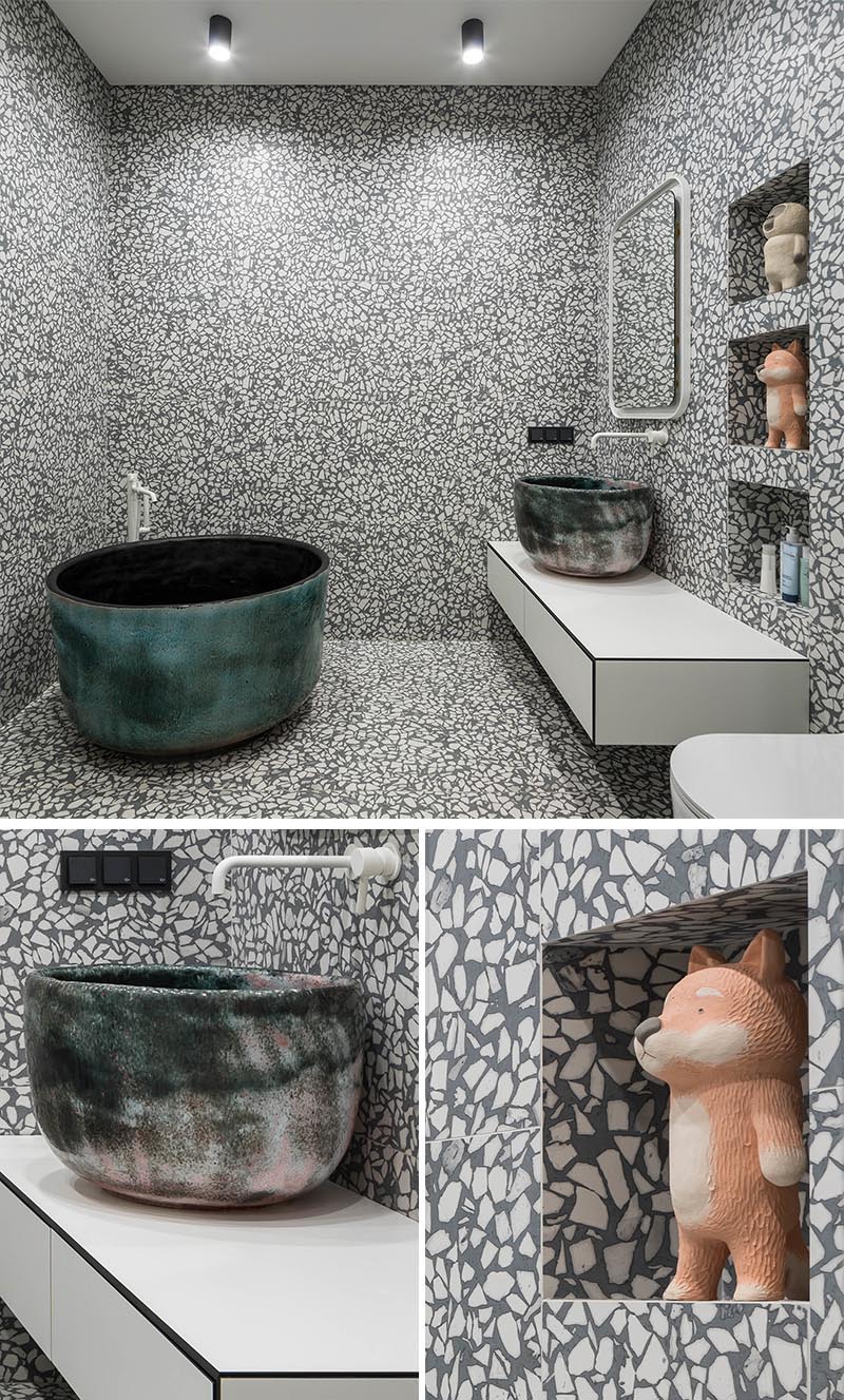 Une tuile de grand format agrégée grise et blanche a été installée dans cette salle de bain moderne et couvre les murs et le sol, créant une expérience presque artistique lors de l'utilisation de la salle de bain. #GreyAndWhiteBathroom #GreyBathroom #BathroomIdeas #SoakingTub #ShelvingNiche #ModernBathroom #FloatingVanity