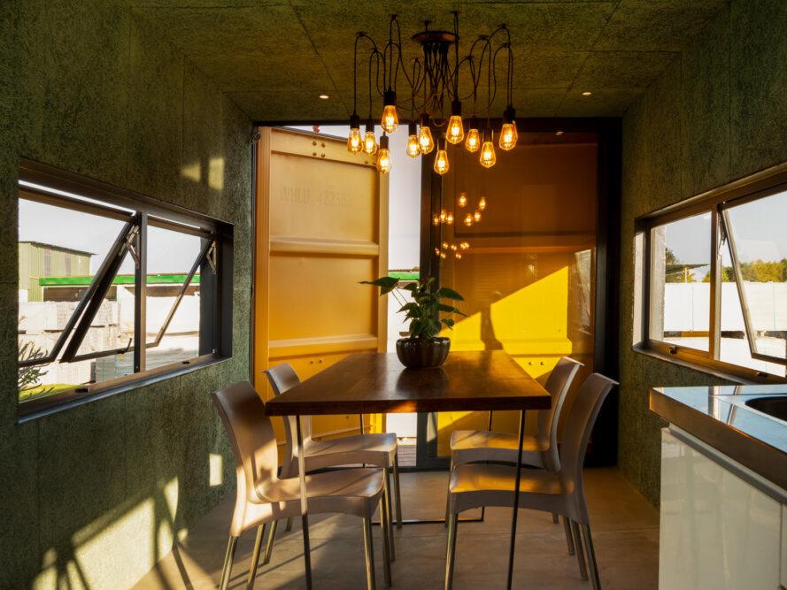 chambre jaune avec petite table à manger sous un lustre moderne