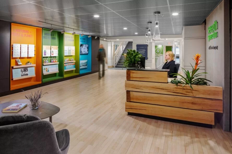 zone de réception de bureau avec bureau en bois et affichage mural coloré des produits et valeurs de la septième génération