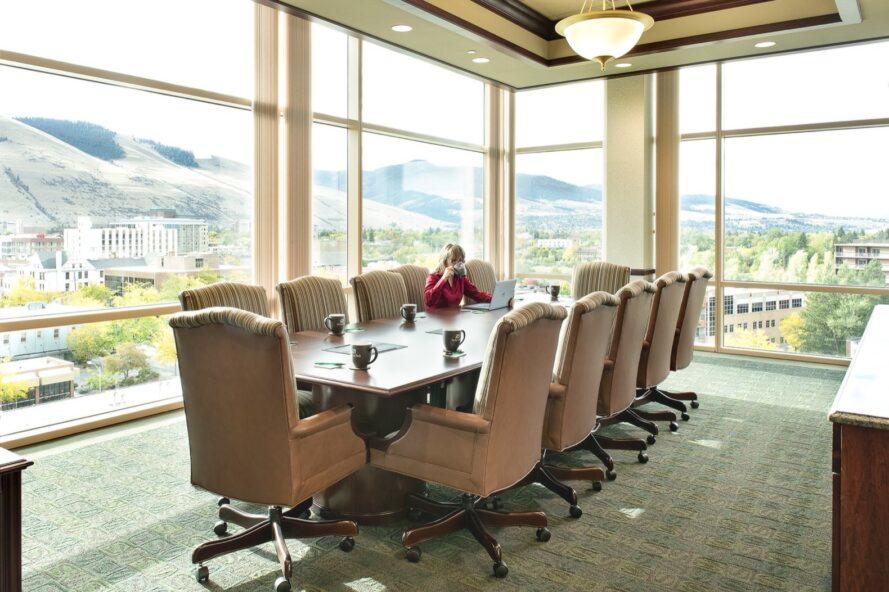 grande table de réunion avec des chaises de bronzage dans le bureau avec des murs en verre