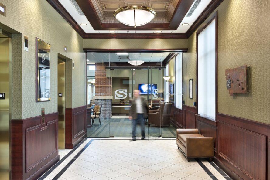 personne qui marche dans une banque avec un décor marron et beige