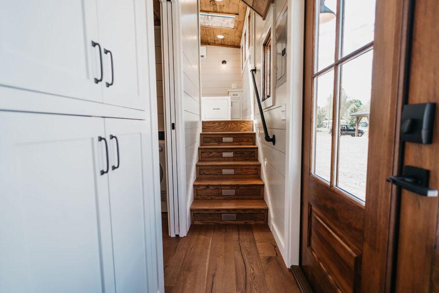 un couloir blanc avec des escaliers en bois