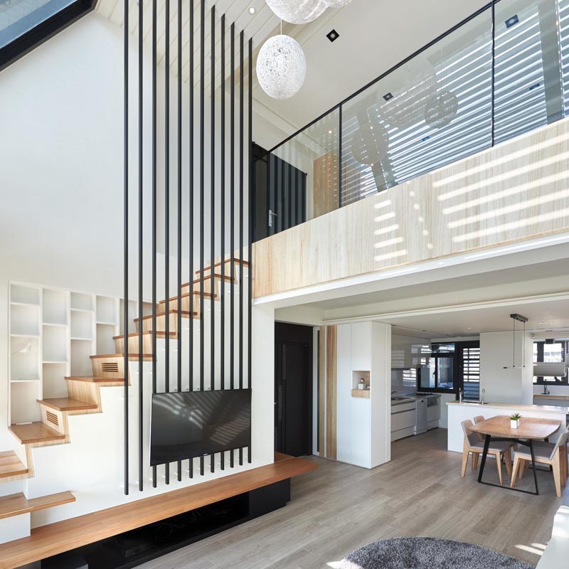 La firme de design d'intérieur INDOT a conçu un appartement moderne à Taïwan, qui présente une collection audacieuse de 12 poteaux noirs qui voyagent du salon jusqu'au haut plafond. #HighCeiling #TVMount #StairDesign