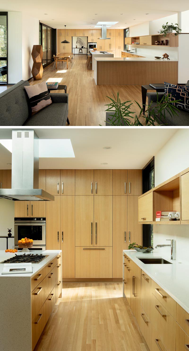 La salle à manger et la cuisine de cet intérieur moderne sont spacieuses, avec une cuisine conçue avec des armoires en chêne faites à la main, des comptoirs en quartz et une paire de puits de lumière. #ModernWoodKitchen #QuartzCountertops #ModernKitchen #LightWoodKitchen