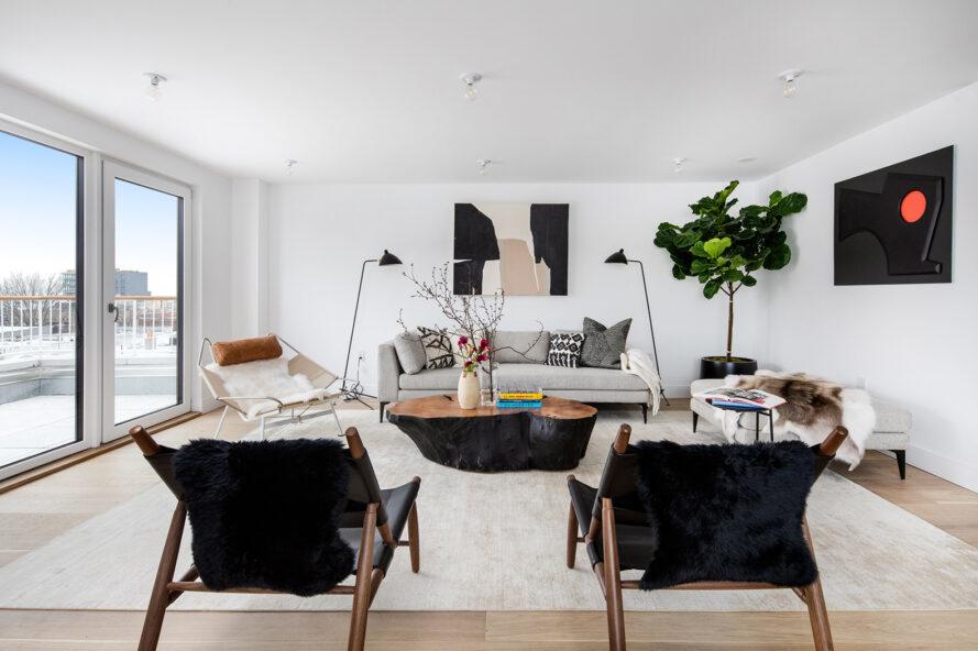 chambre blanche avec des chaises en fourrure noire et un canapé gris