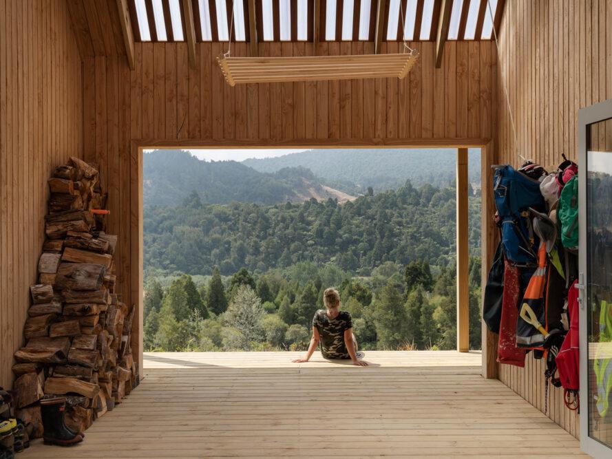 Personne assise sur une terrasse en bois couverte donnant sur les montagnes
