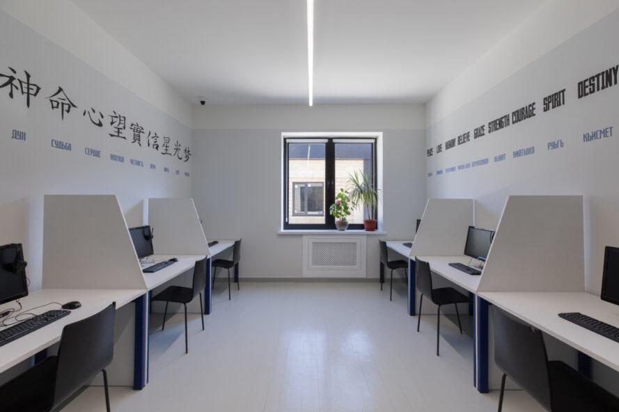 Salle de classe blanche avec des ordinateurs sur des bureaux contre chaque mur