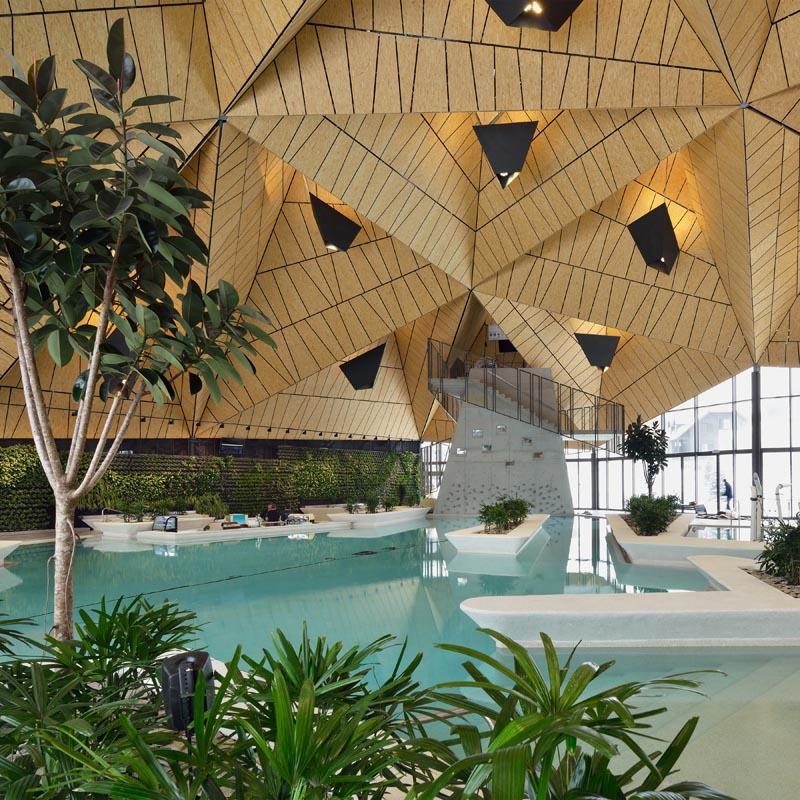 Une piscine publique avec un plafond en bois angulaire.