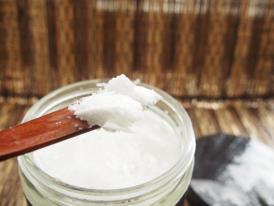 Personne ramasser l'huile de noix de coco dans un pot avec une cuillère en bois