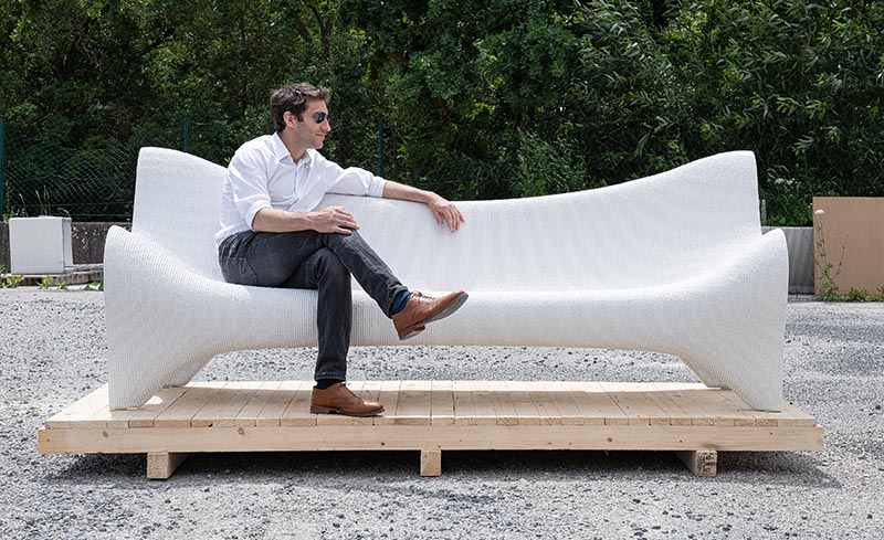 Un canapé d'extérieur en béton blanc réalisé à l'aide de techniques d'impression 3D.
