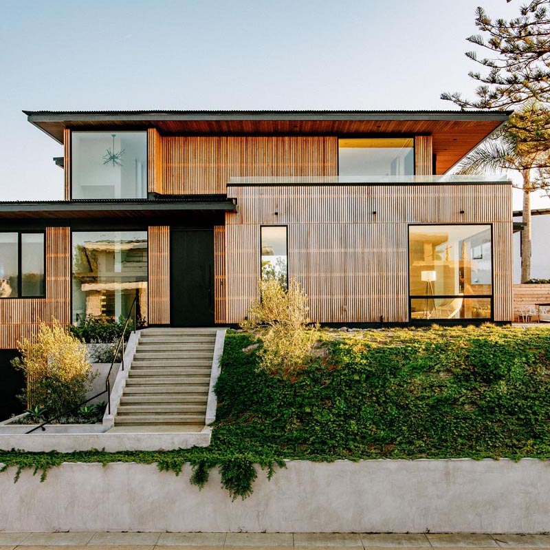 Une maison avec une façade en lattes de bois de cèdre a des accents noirs et des avant-toits en surplomb.