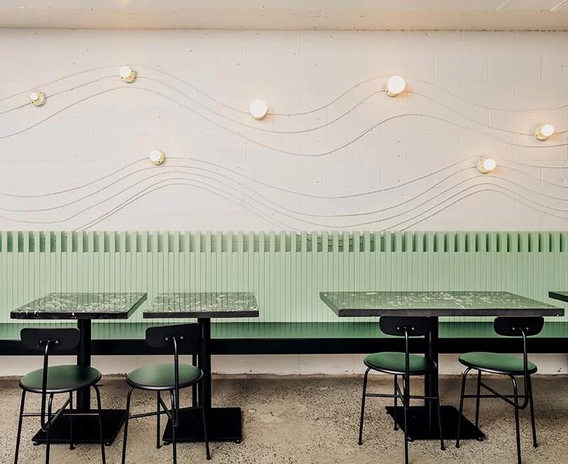 Cette conception de restaurant moderne utilise des conduits électriques et des luminaires sans clé pour créer un art mural attrayant qui trace légèrement la forme d'une vague.