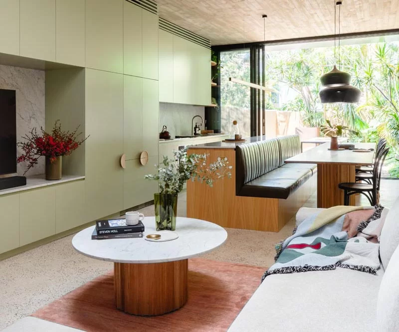 Une cuisine moderne vert clair avec un îlot qui se transforme en banc pour table à manger.