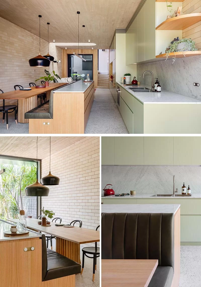 Une cuisine vert clair a un îlot en bois qui se transforme en un banc de banquette pour la table à manger.