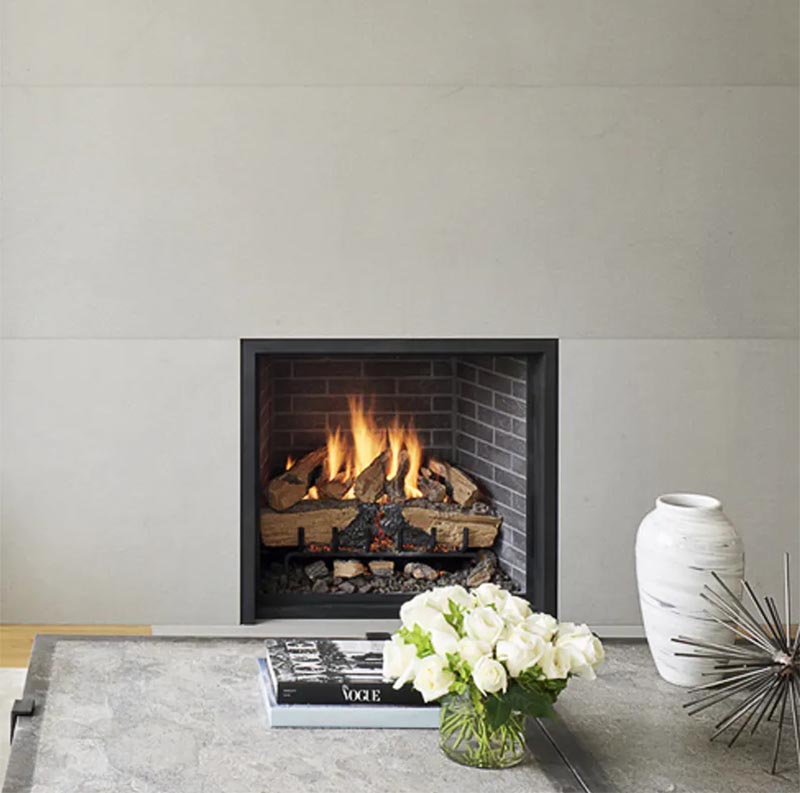 Un contour de cheminée gris, qui se déplace du sol au plafond, contraste le cadre noir et la brique sombre de la cheminée