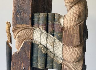 Un serpent à sonnettes serpente s’enroule autour d’une sculpture métaphorique en bois et en livre de Maskull Lasserre